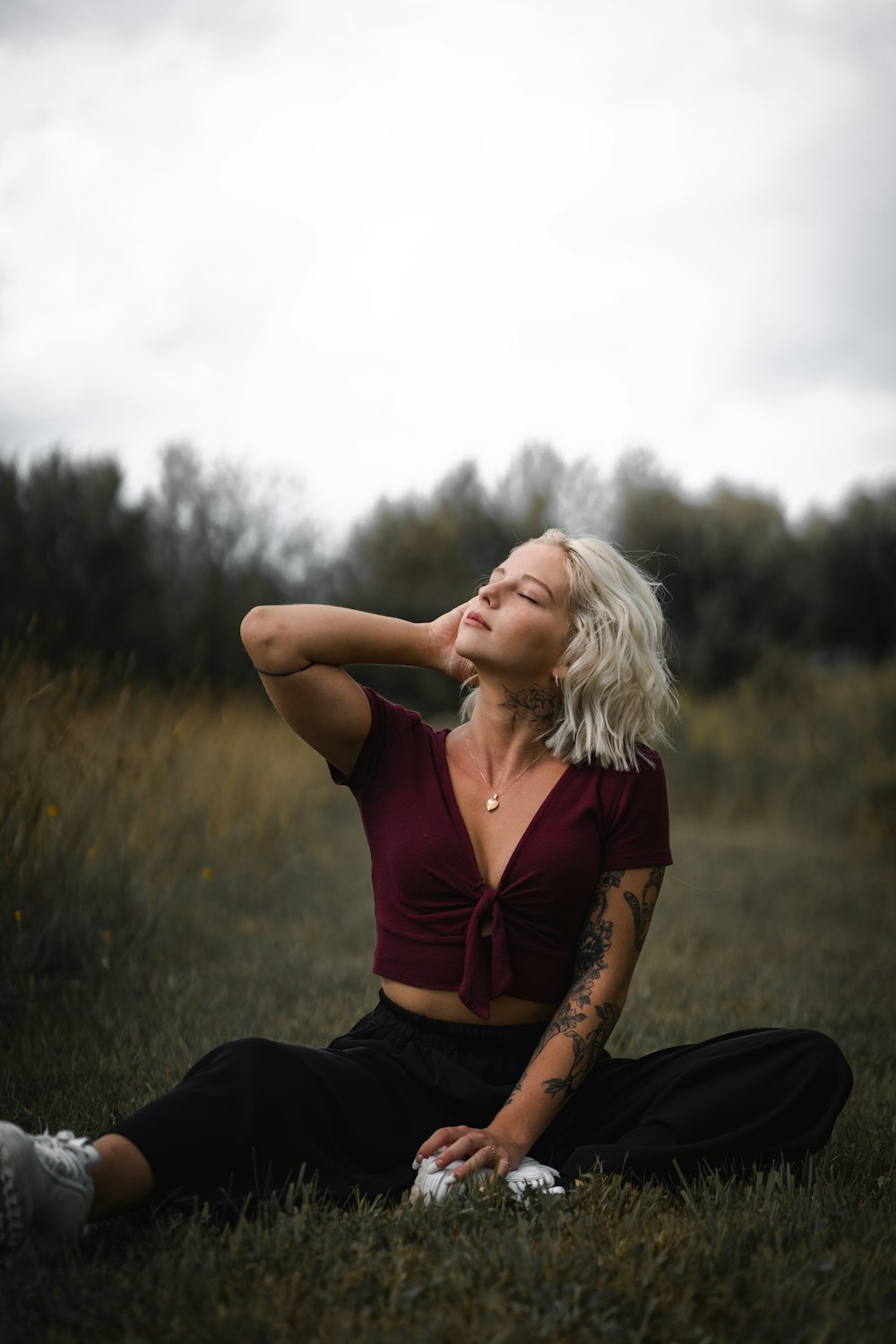 woman in brown shirt and black pants sitting on grass field during daytime