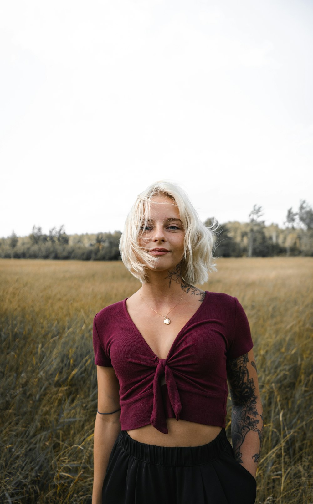 woman in red scoop neck shirt standing on brown grass field during daytime