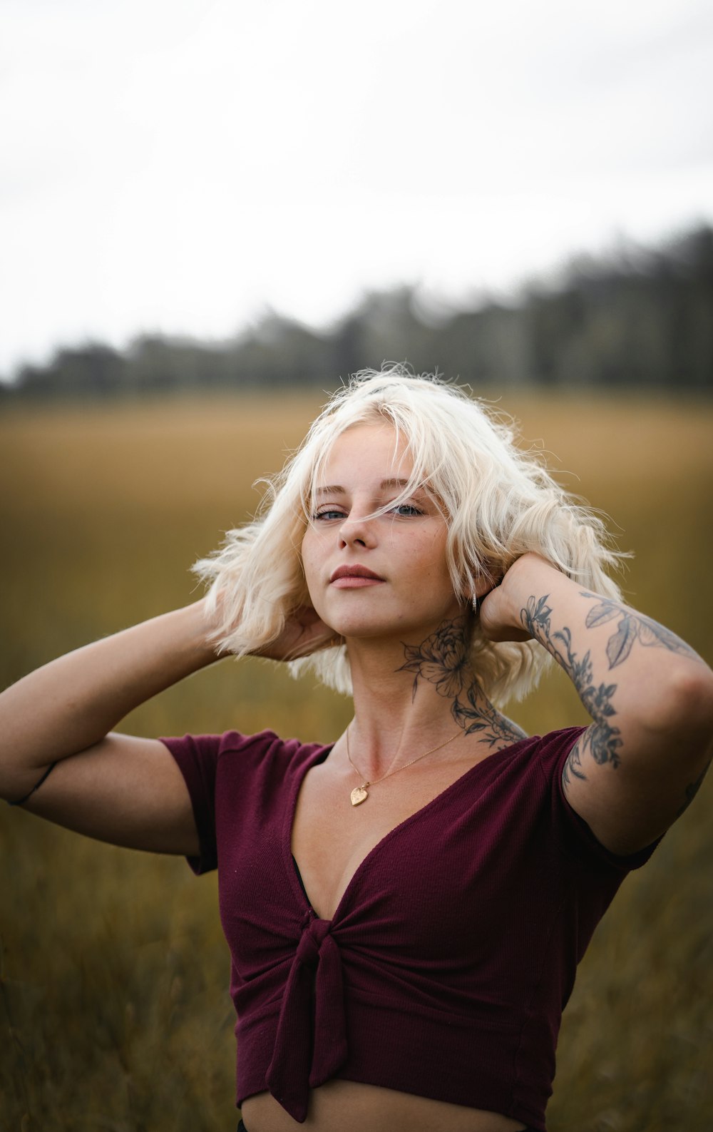 woman in maroon scoop neck shirt with right hand on head