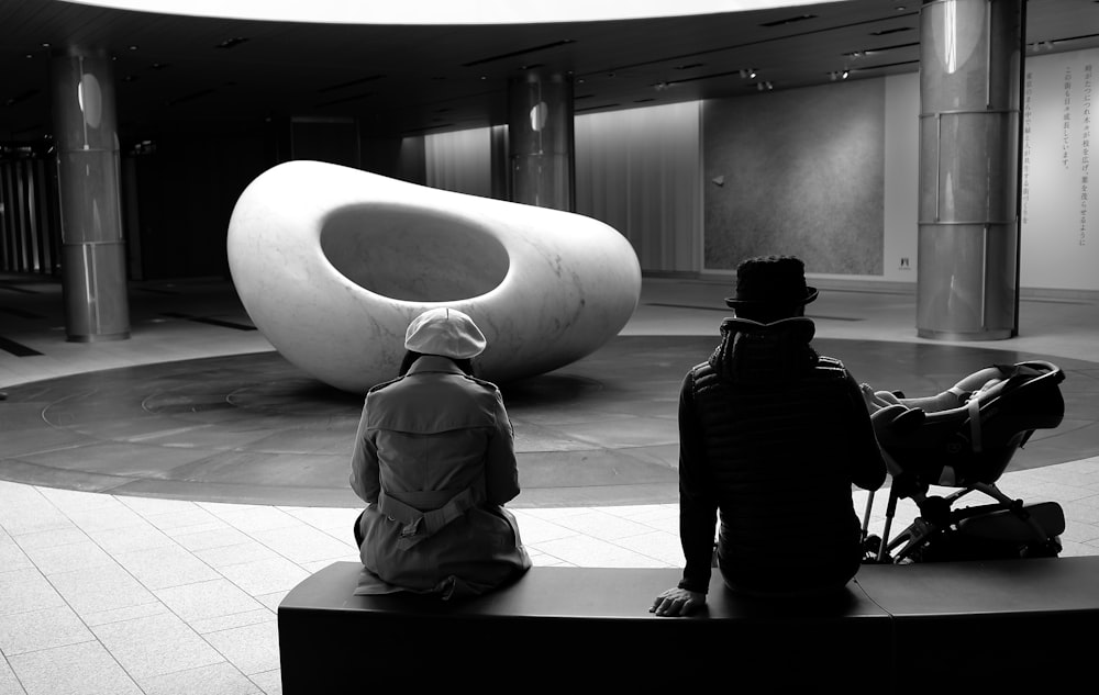 man in black jacket and pants sitting on white bench