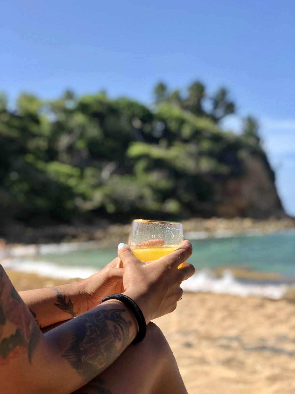 person holding clear drinking glass with yellow liquid