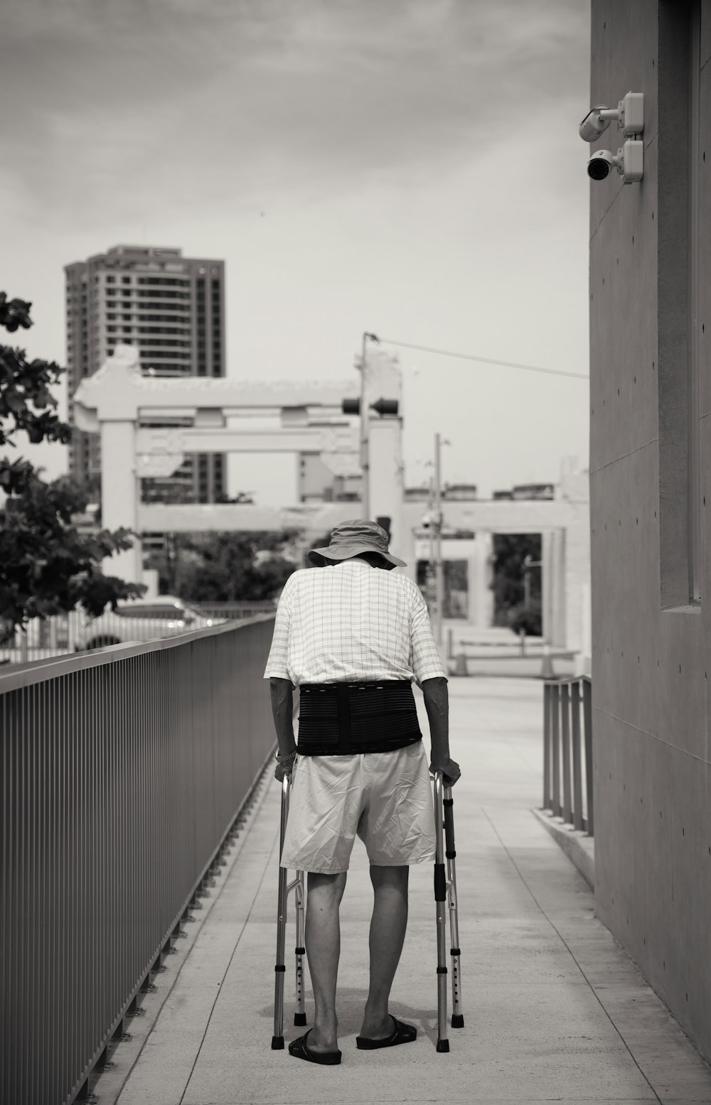 Photo en niveaux de gris d’un homme en chemise à manches longues à carreaux noir et blanc et pantalon noir debout