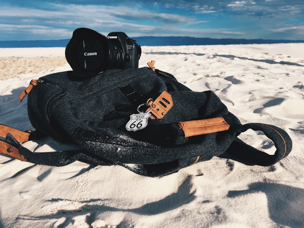 black and brown backpack on white sand during daytime