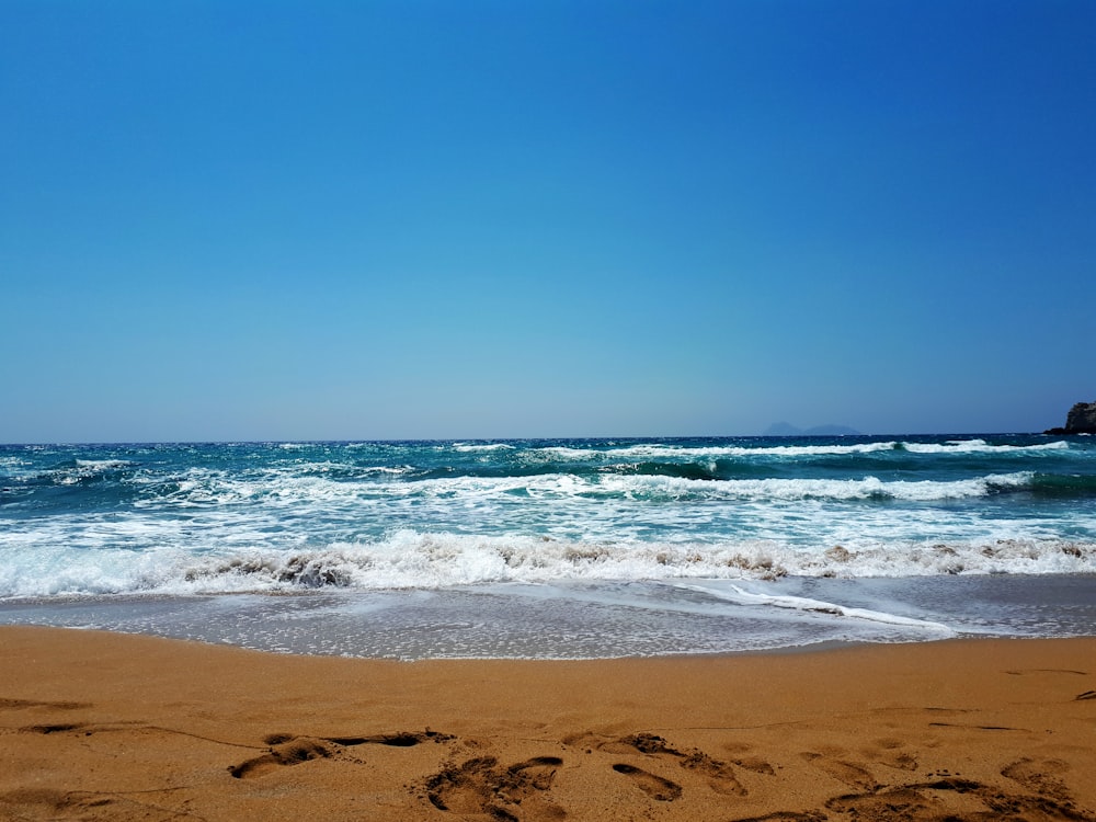 sea waves crashing on shore during daytime