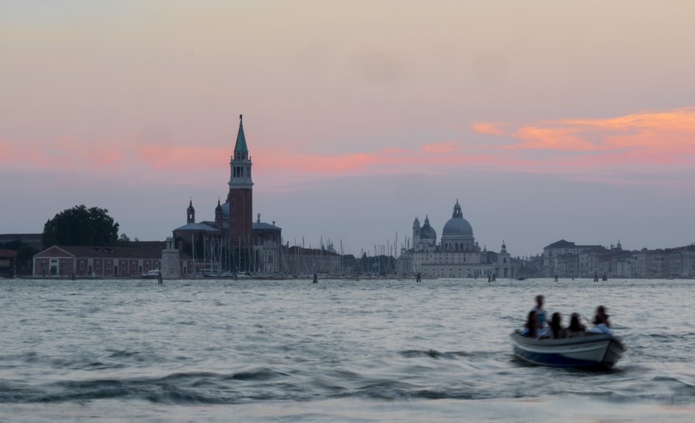 people riding on boat on water near city buildings during daytime