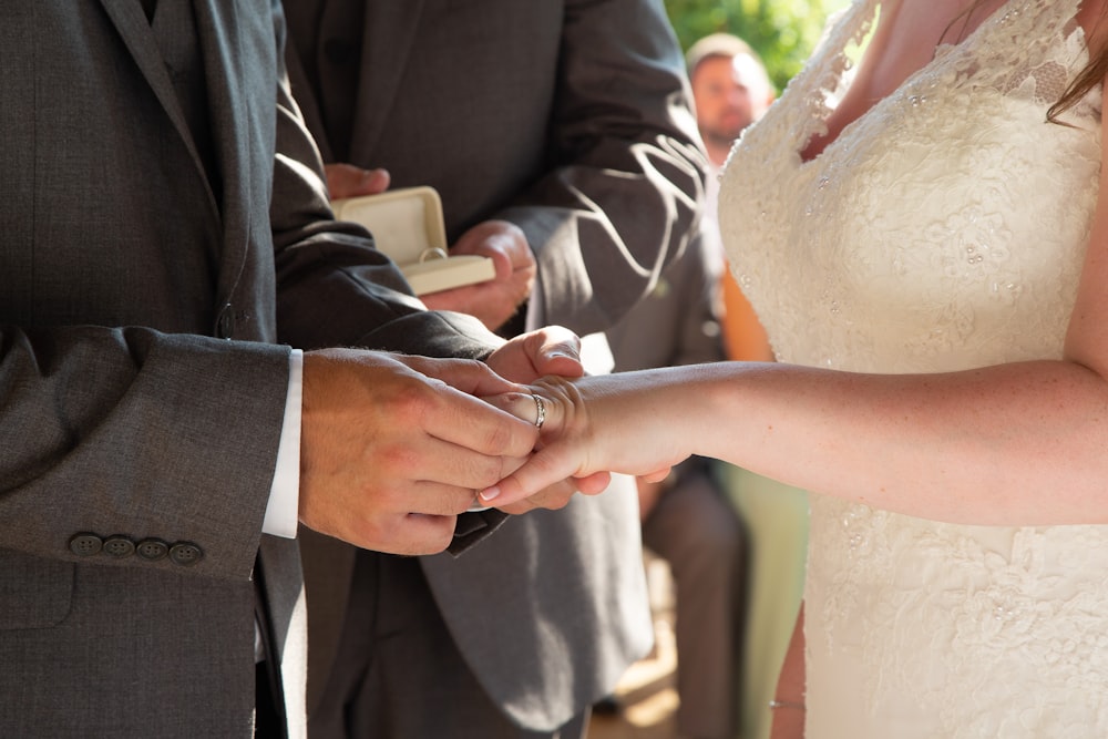 man in black suit jacket holding womans hand