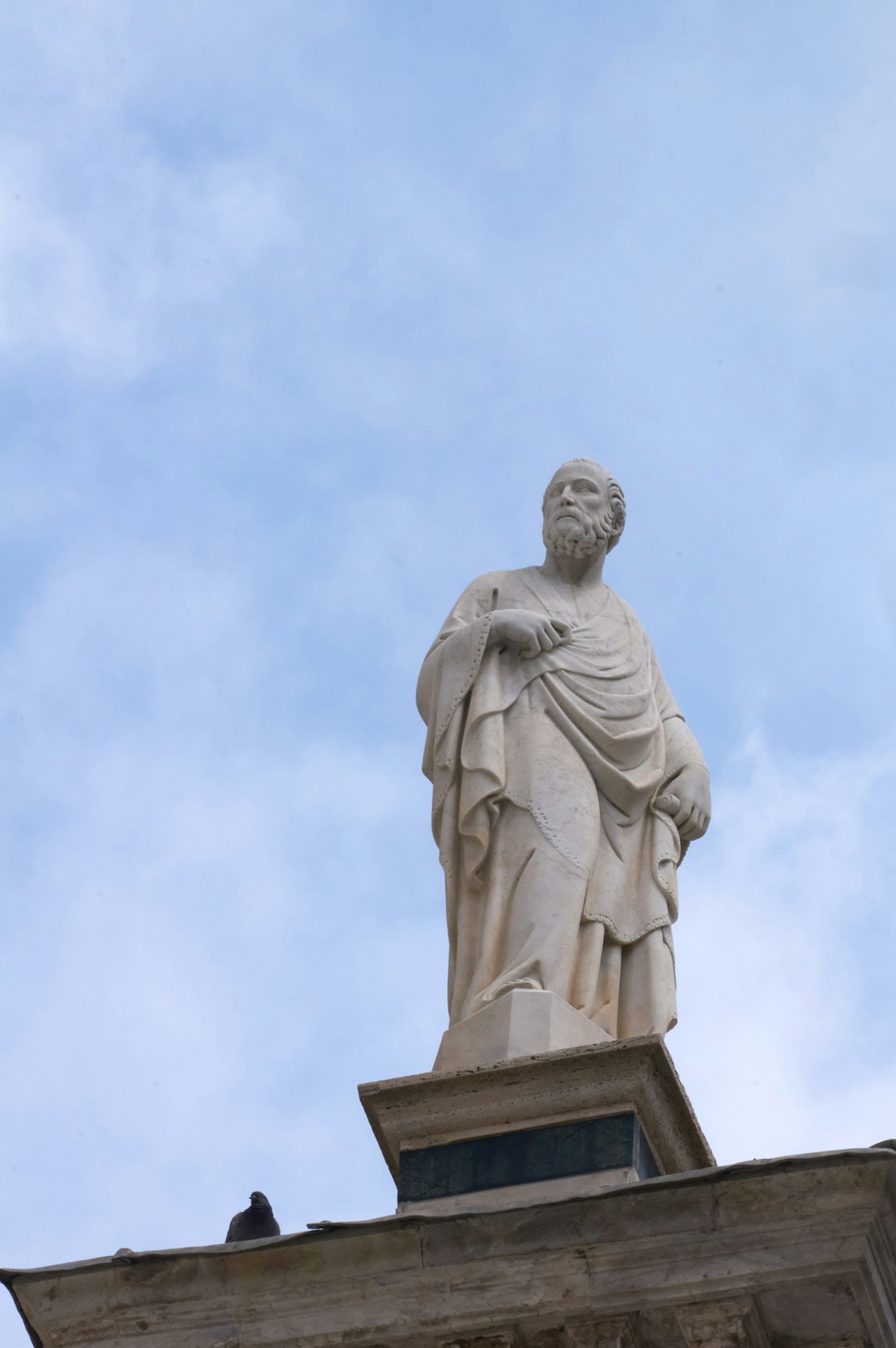 man in robe statue under white sky during daytime