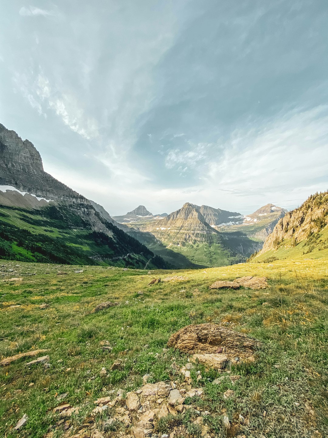 green grass field near mountain under white clouds during daytime