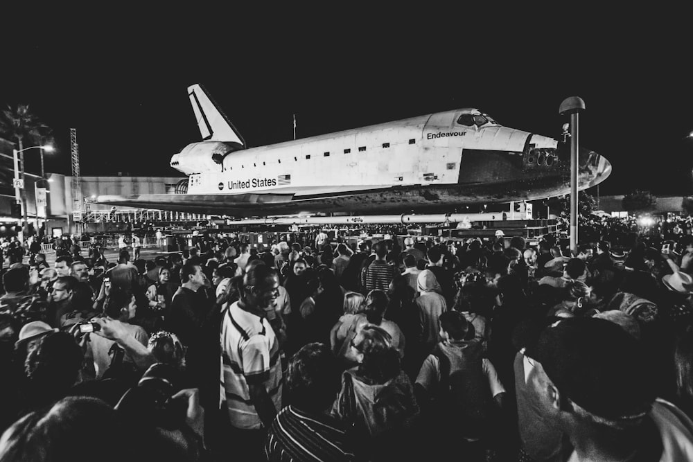 grayscale photo of people in front of white airplane