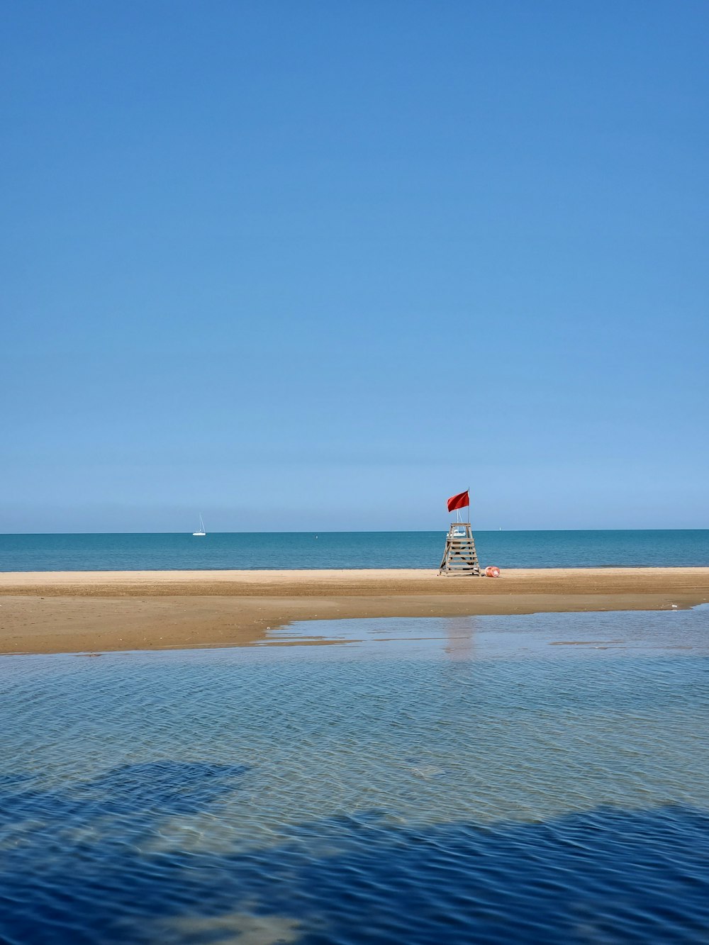 white and red lighthouse on brown sand under blue sky during daytime