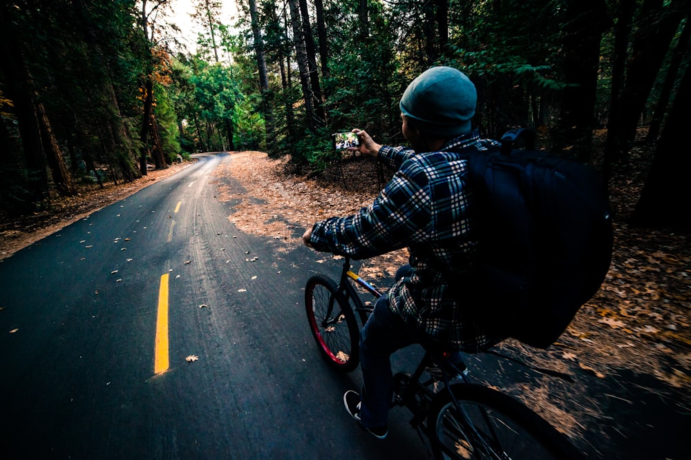 man in black and white plaid dress shirt riding on black bicycle on road during daytime