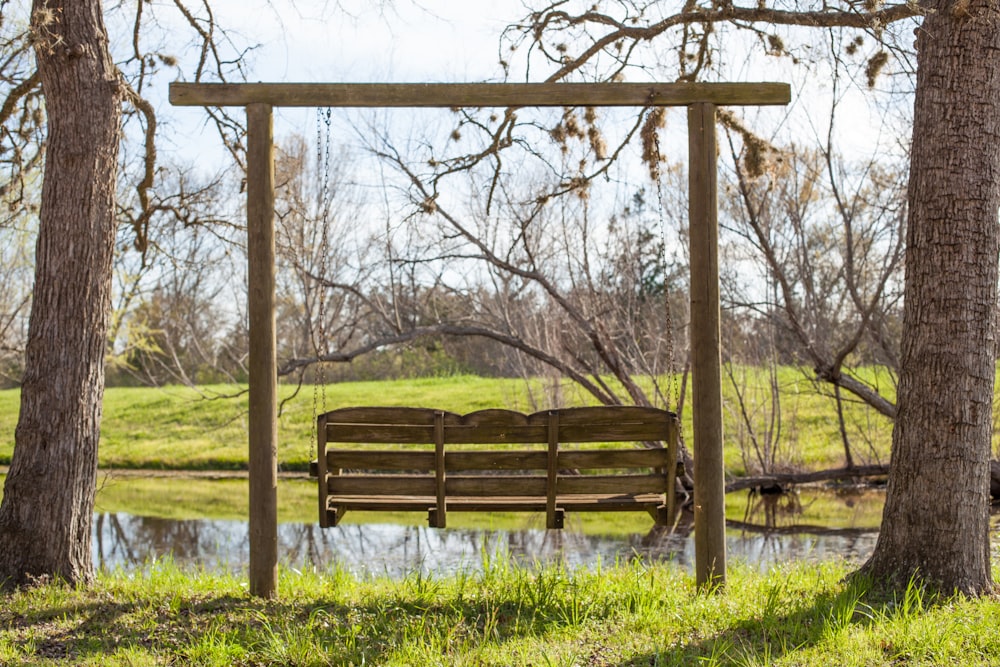 banc en bois brun sur un champ d’herbe verte pendant la journée