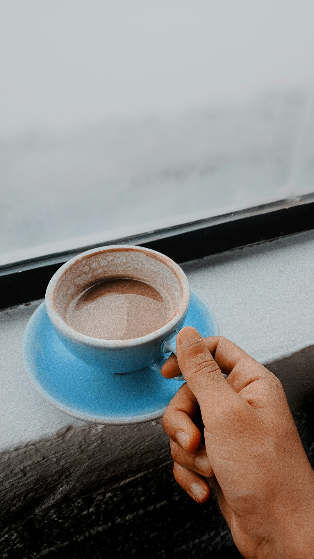 person holding blue ceramic mug with coffee