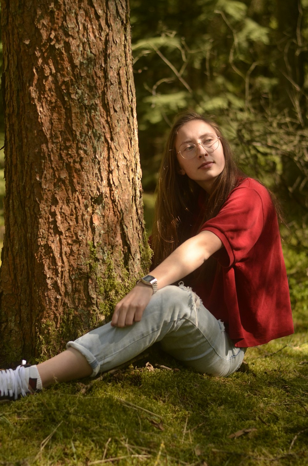 woman in red shirt and blue denim jeans sitting on green grass field