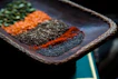 Close-up of polished Indonesian spices arranged neatly on a dark wooden table.