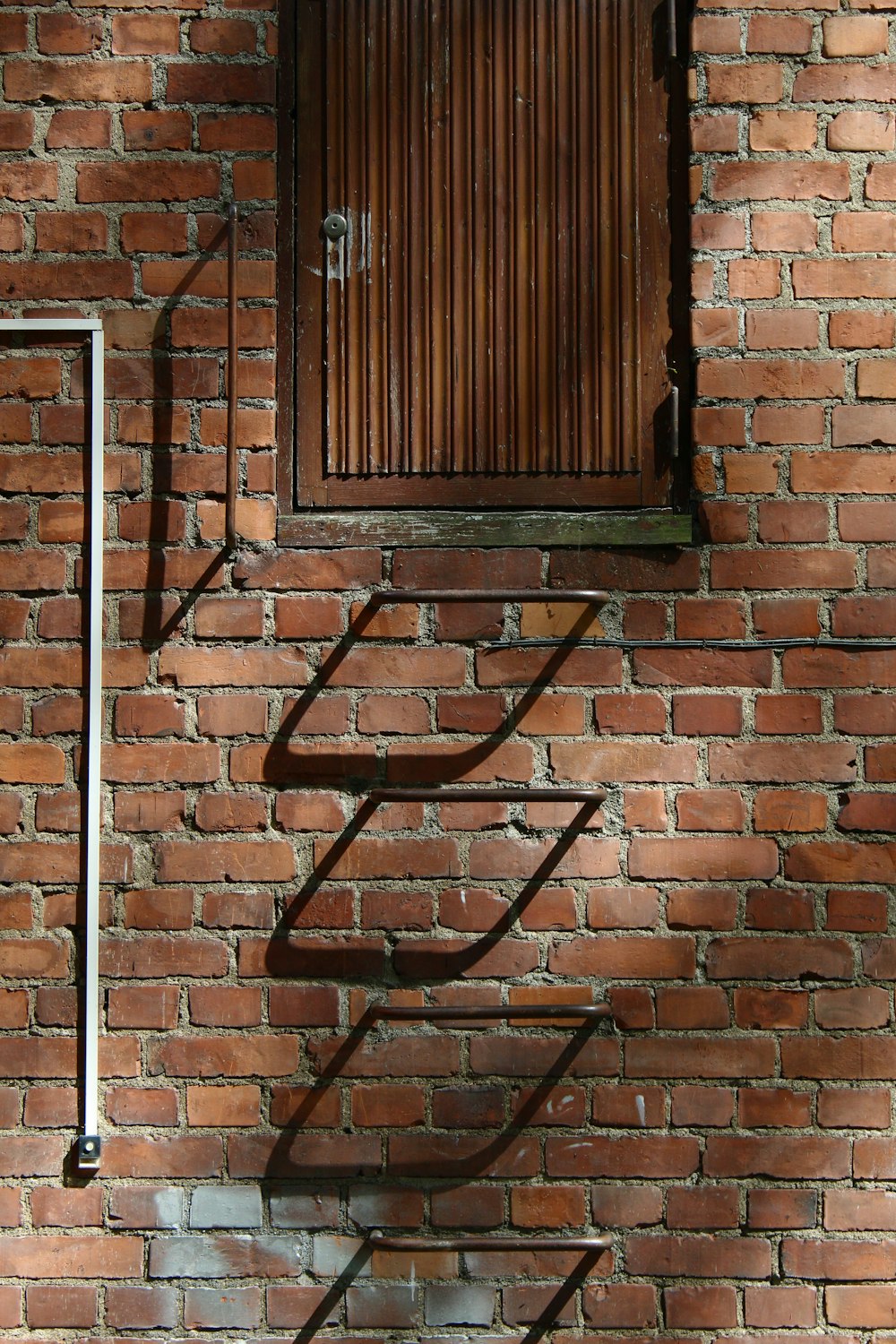 Cadre de fenêtre en métal noir sur mur de briques brunes
