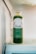 A bottle of green juice labeled 'Verde' sits inside a refrigerator. The label indicates it is fresh-pressed juice and wellness shots from Long Beach, CA. The clear bottle allows the green liquid to be visible, and the top is sealed with a metallic cap.