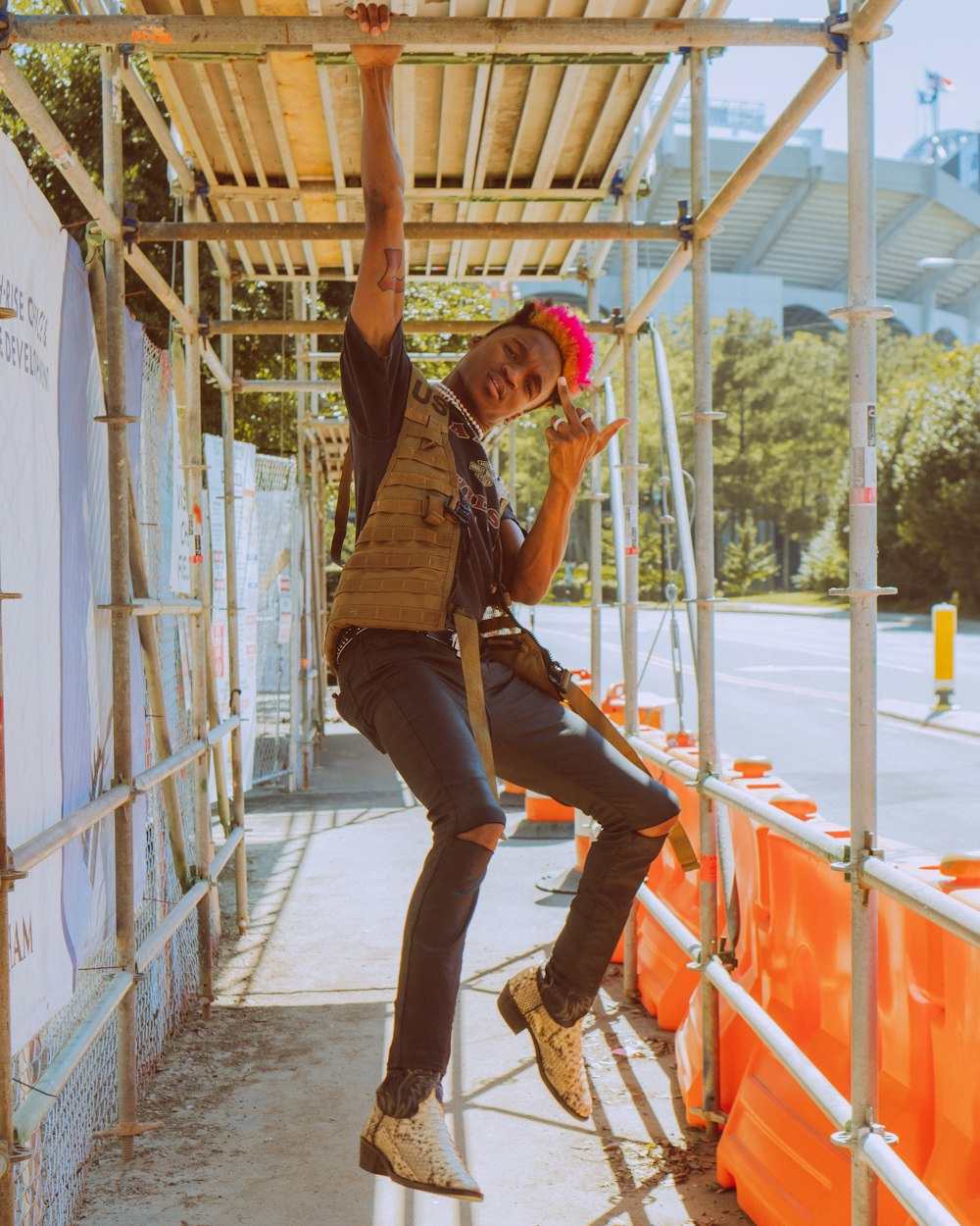 man in brown t-shirt and blue denim jeans sitting on blue metal railings during daytime