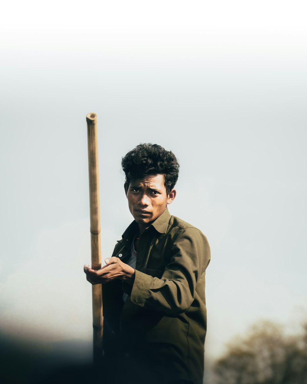 man in brown jacket holding brown wooden stick