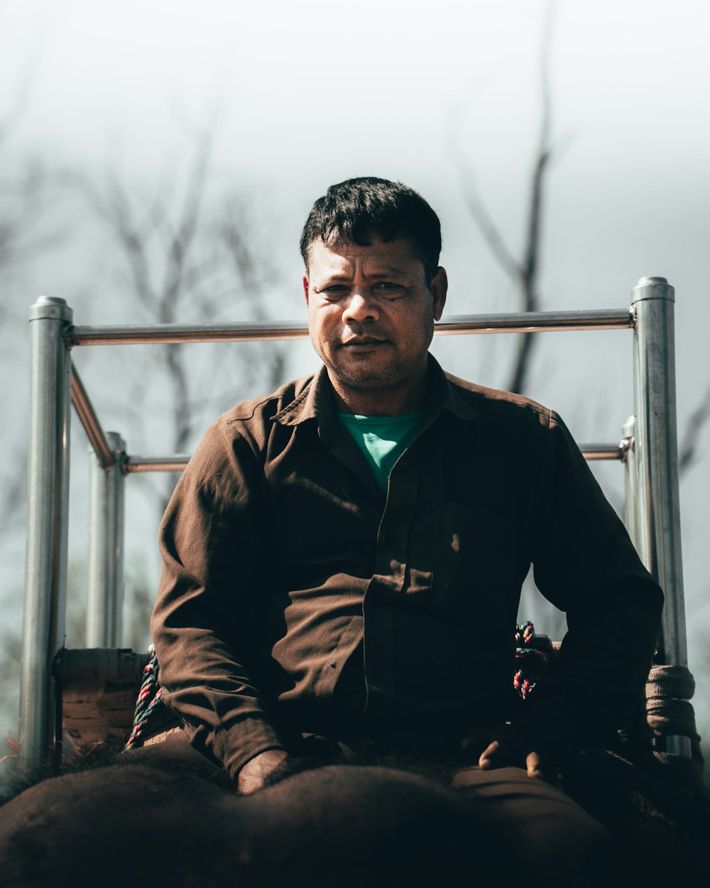 man in black and brown zip up jacket sitting on brown wooden bench during daytime