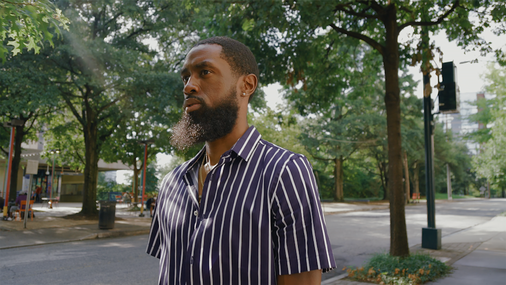 man in black and white striped dress shirt standing near green trees during daytime