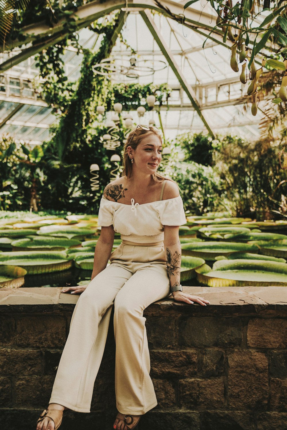 woman in white tank top and beige pants sitting on brown wooden bench