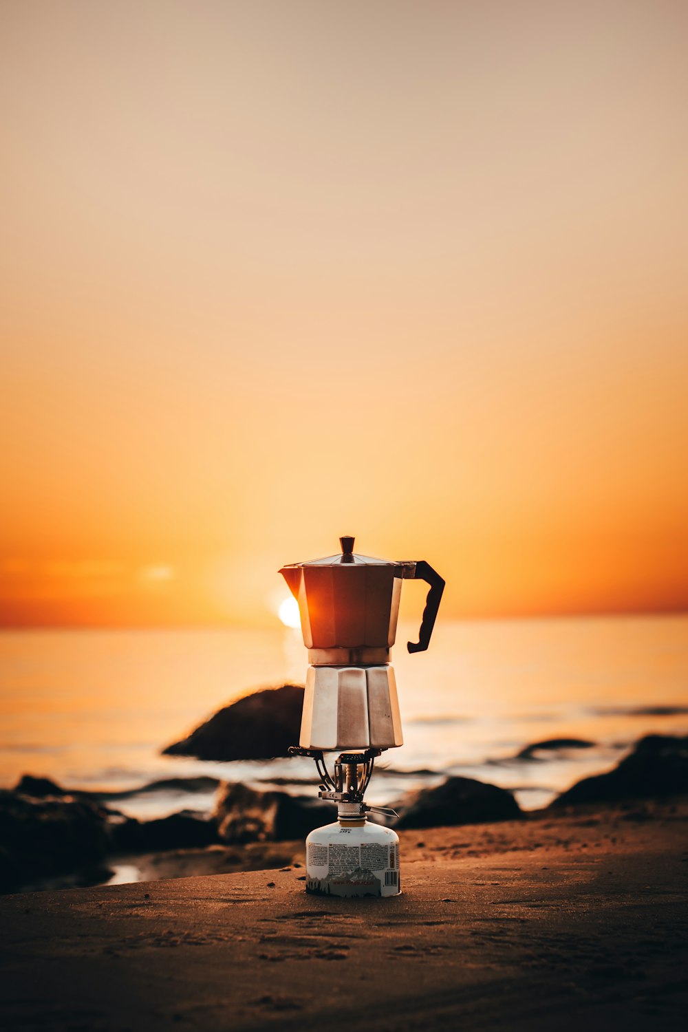 black and silver lantern on brown sand during sunset