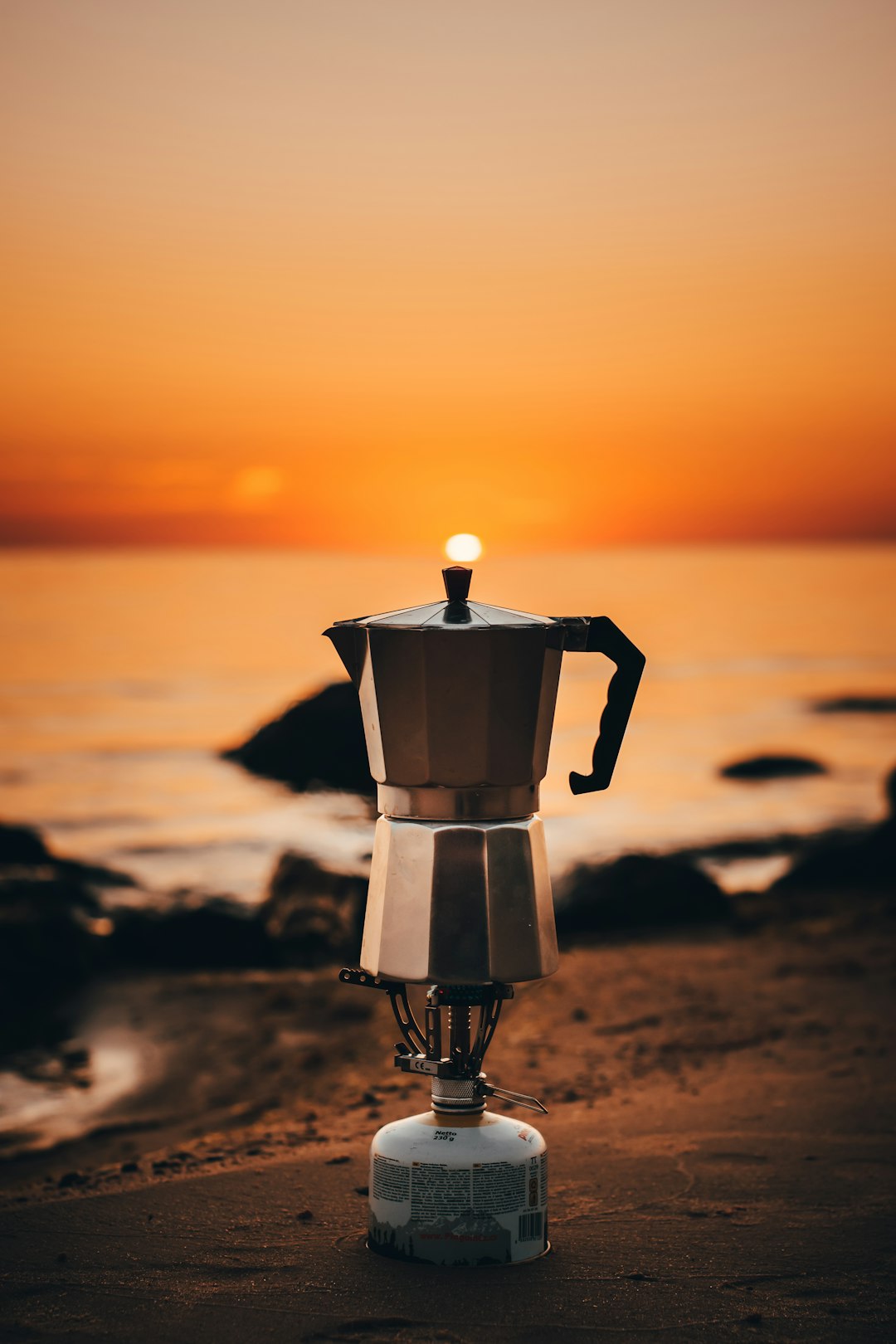 gray and black coffee maker on brown sand during sunset