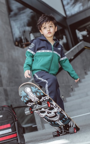 boy in green and blue zip up jacket riding on red and black motorcycle