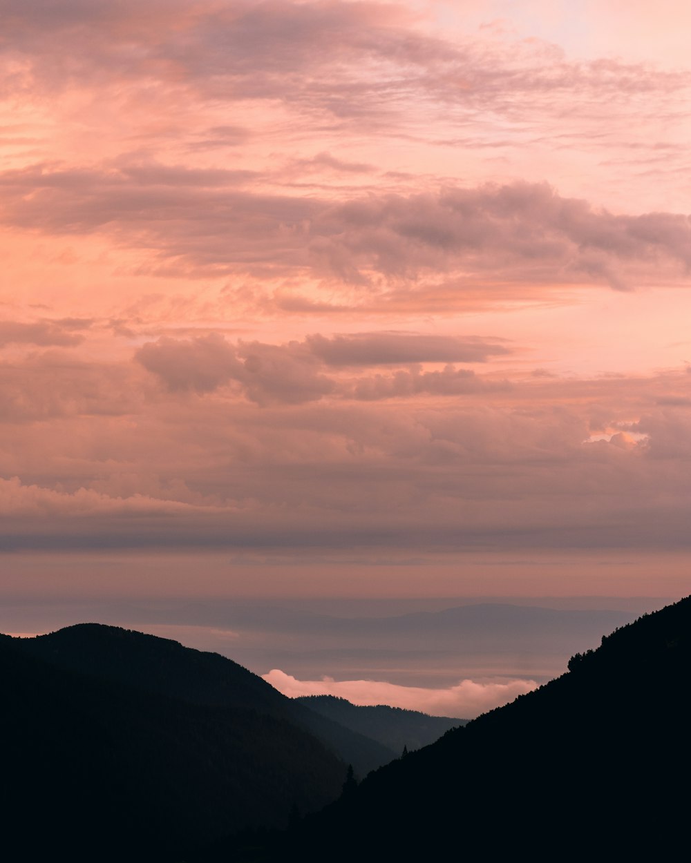 silhouette of mountains under cloudy sky during sunset