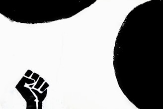 A black silhouette of a raised clenched fist against a stark white background with bold black shapes.