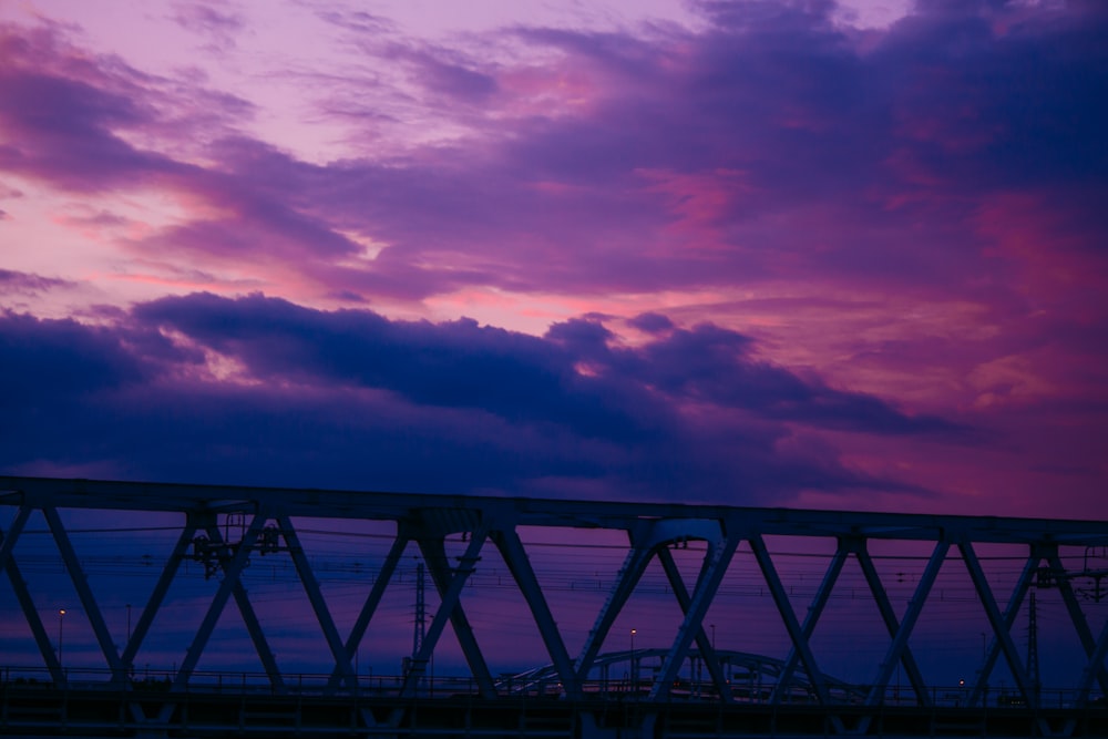 silhouette of bridge under cloudy sky during sunset