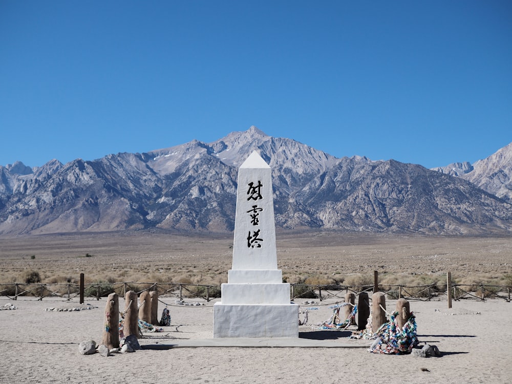 white concrete cross on brown field under blue sky during daytime