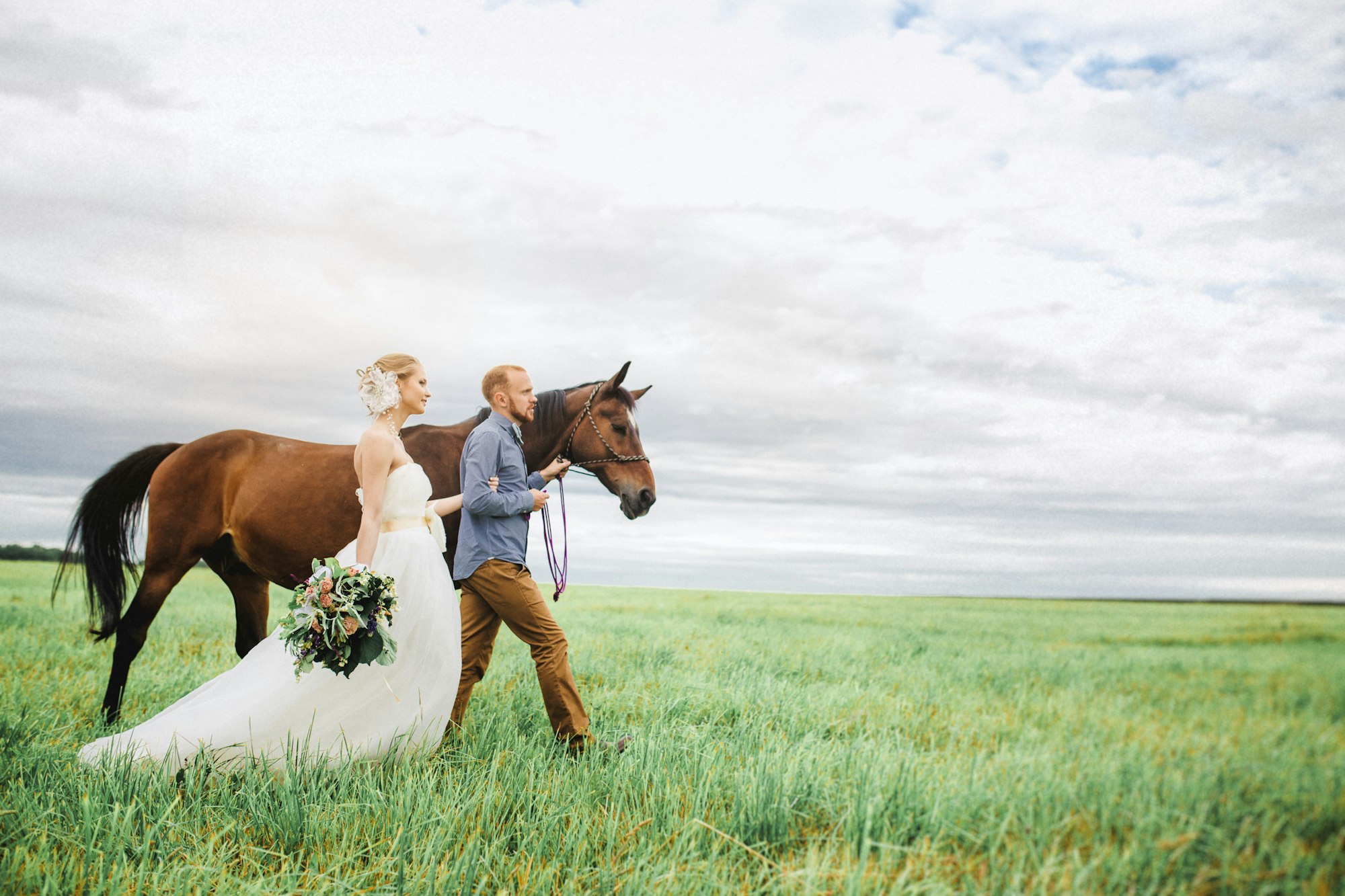 woman in white dress shirt and brown pants riding brown horse on green grass field during