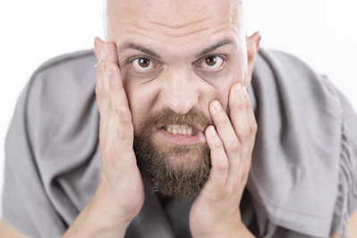 man in gray dress shirt covering his face