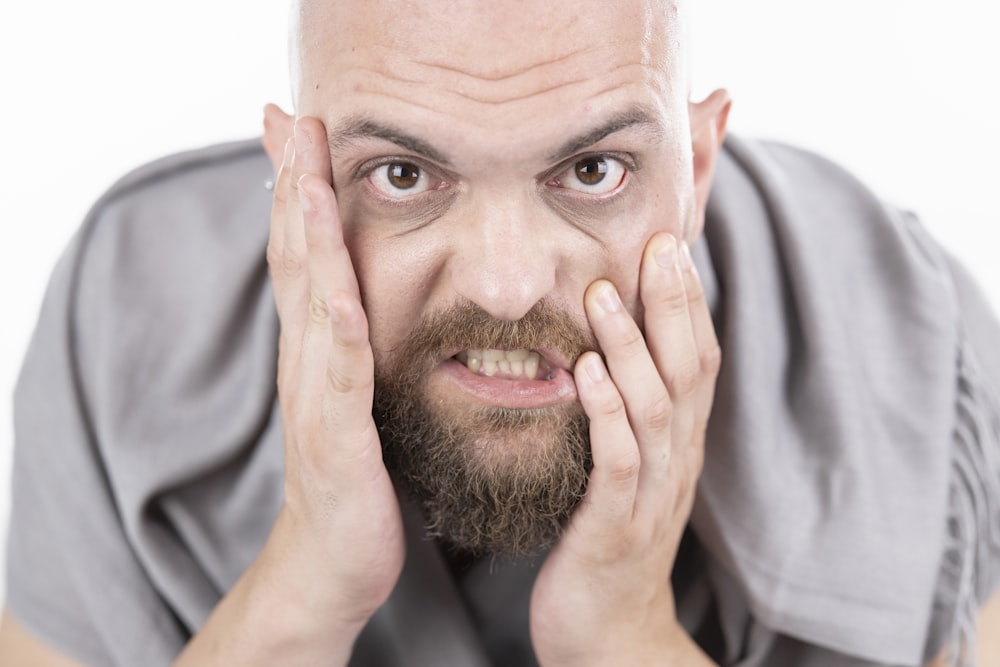 man in gray dress shirt covering his face