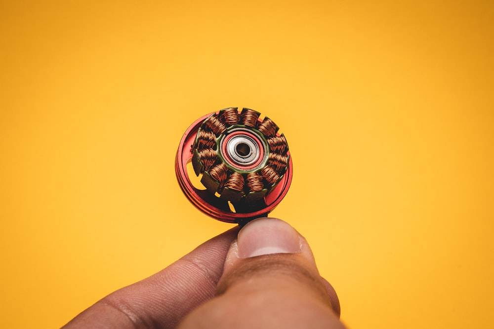 person holding red and yellow round ornament