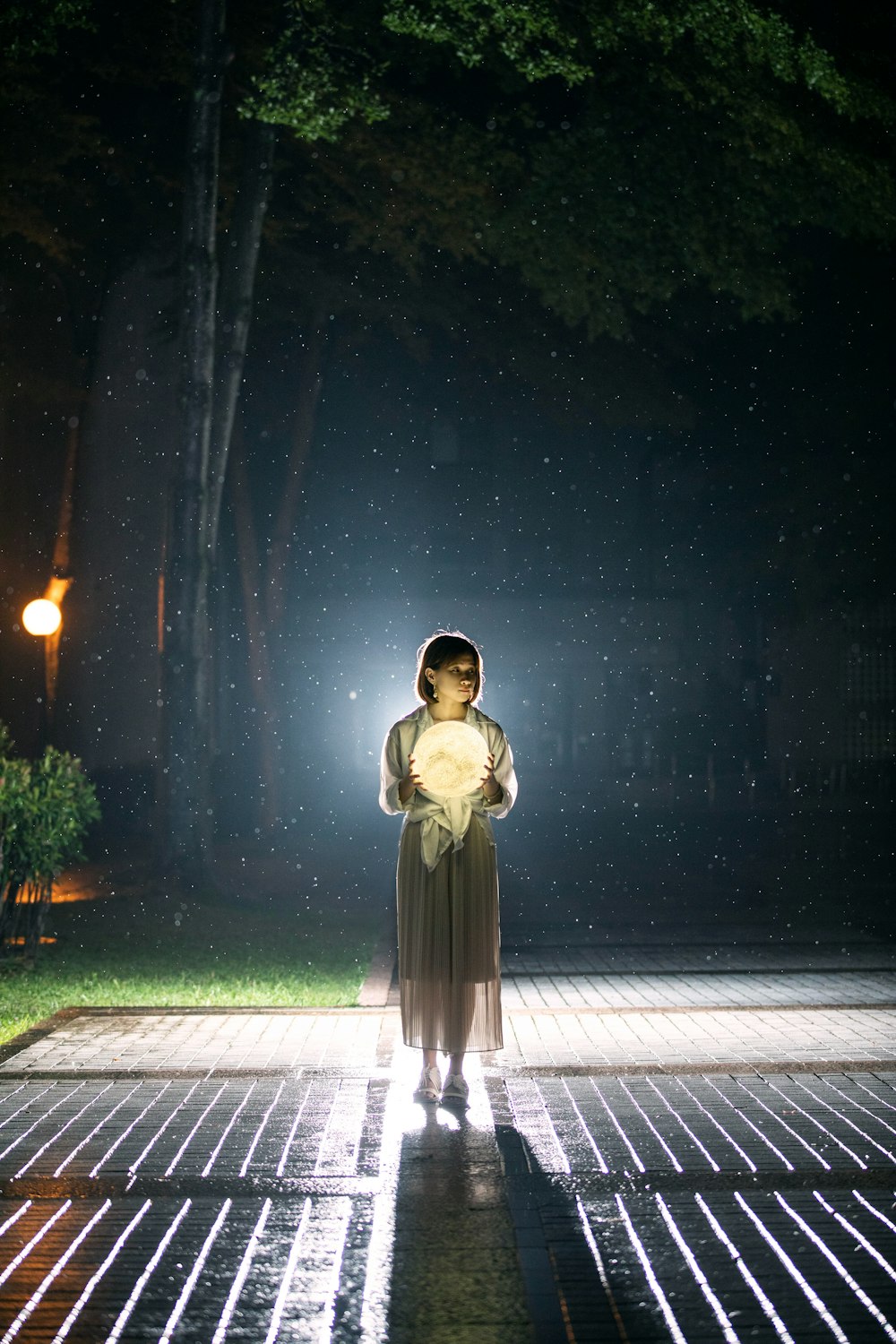 Femme en robe blanche à manches longues debout sur le trottoir pendant la nuit