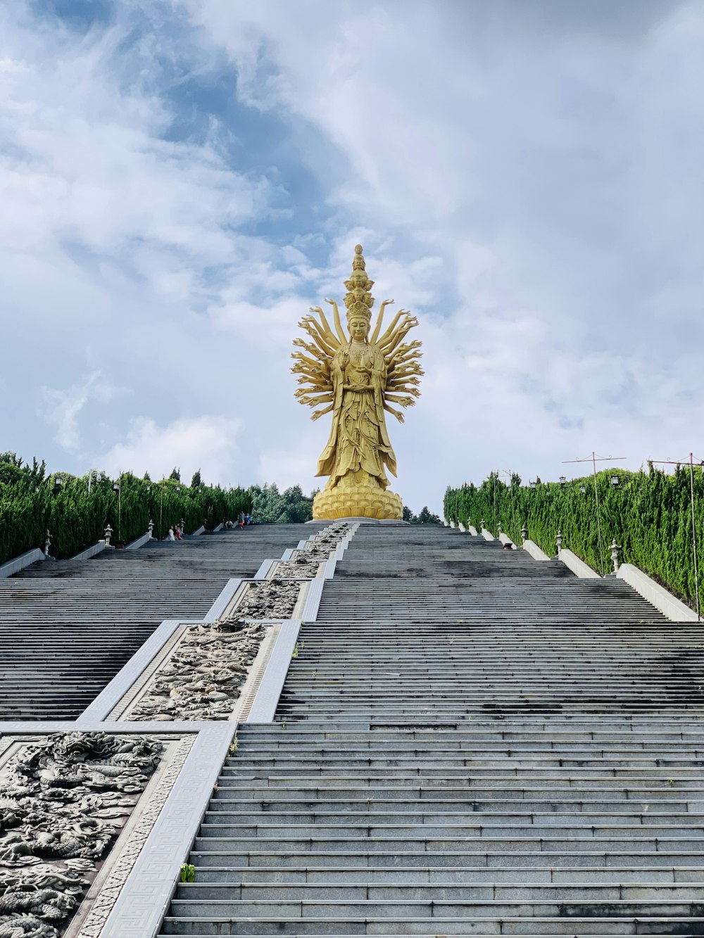 gold statue on wooden dock under cloudy sky during daytime