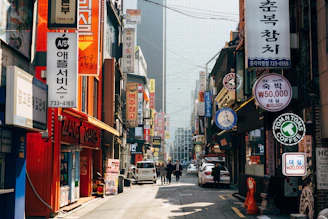 A bustling street in Seoul lined with trendy cafes, each with unique signage and outdoor seating.