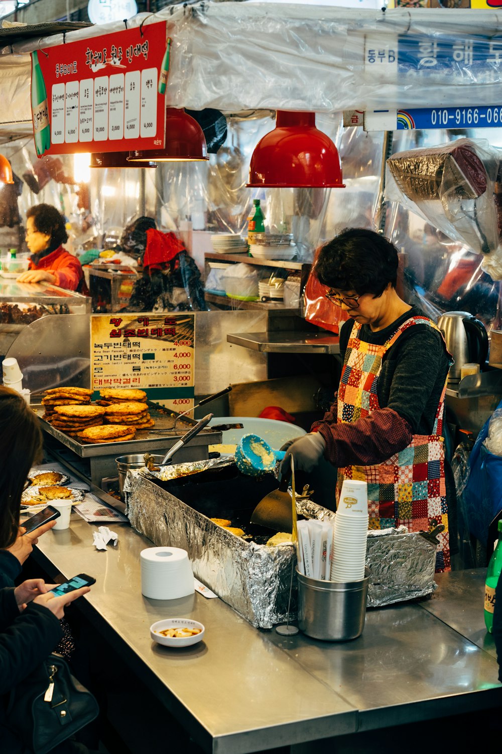 woman in red and black apron holding chopsticks