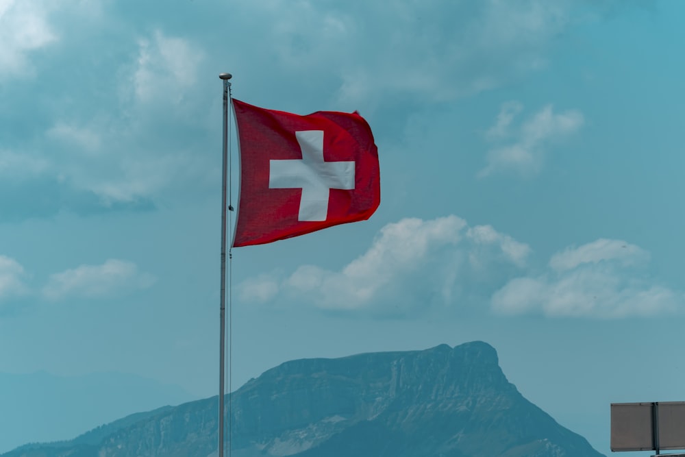 red and white cross flag on pole under blue sky during daytime