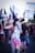 A group of people are gathered, holding Israeli flags. One person in the foreground has covered their face partially with a flag and is wearing striped pants, carrying a colorful toy water gun. The crowd seems engaged in a protest or demonstration as they wave flags and banners.