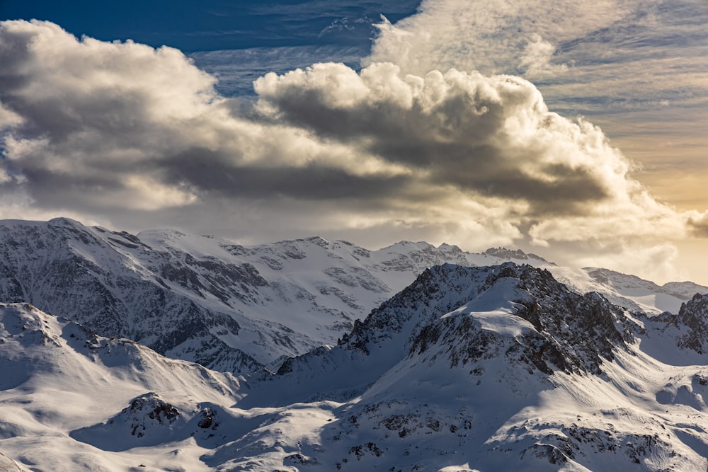 snow covered mountains under white clouds and blue sky during daytime