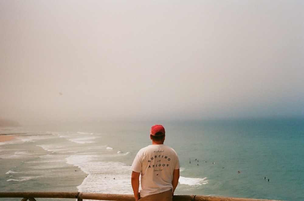 man in white crew neck t-shirt standing on beach during daytime