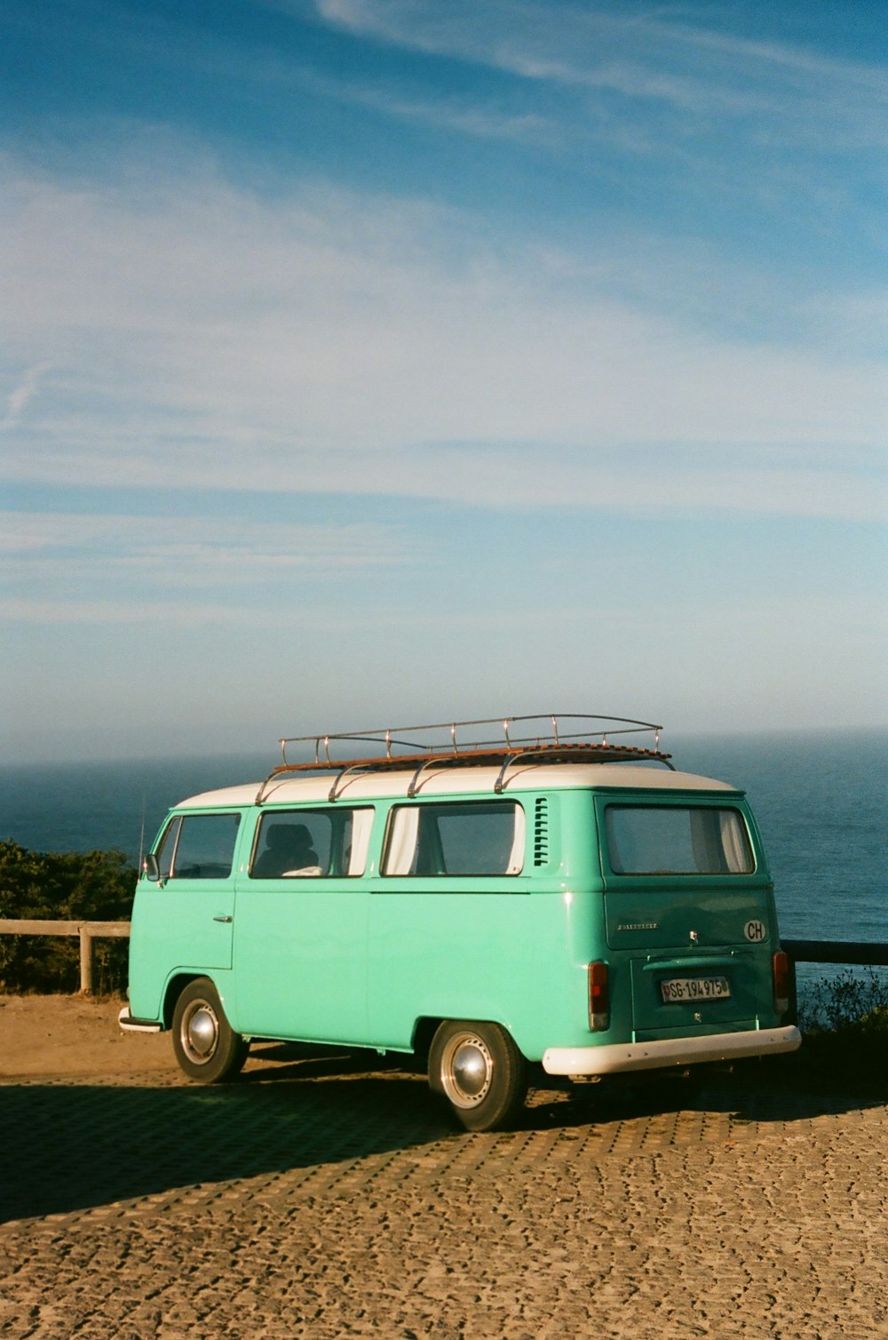 blue and white volkswagen t-2 on green grass field under white clouds during daytime