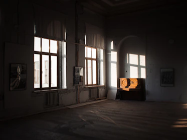 Cozy studio corner with soft beige walls and a gleaming piano illuminated by natural light.