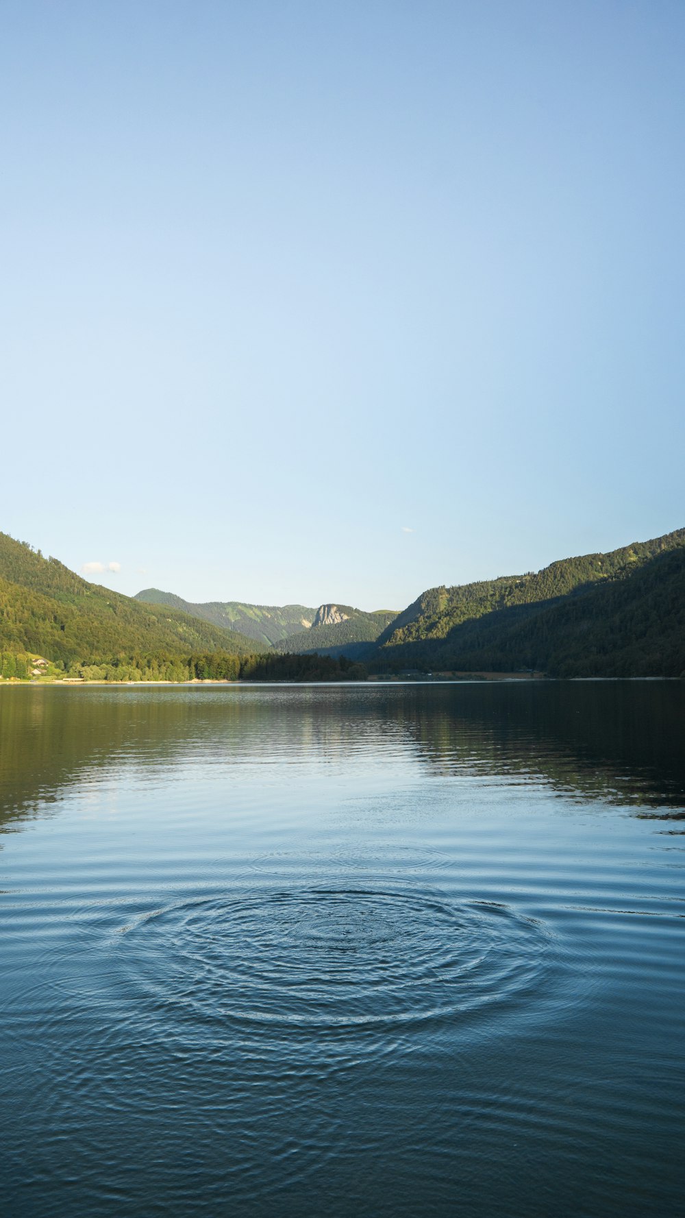 body of water near green mountain during daytime