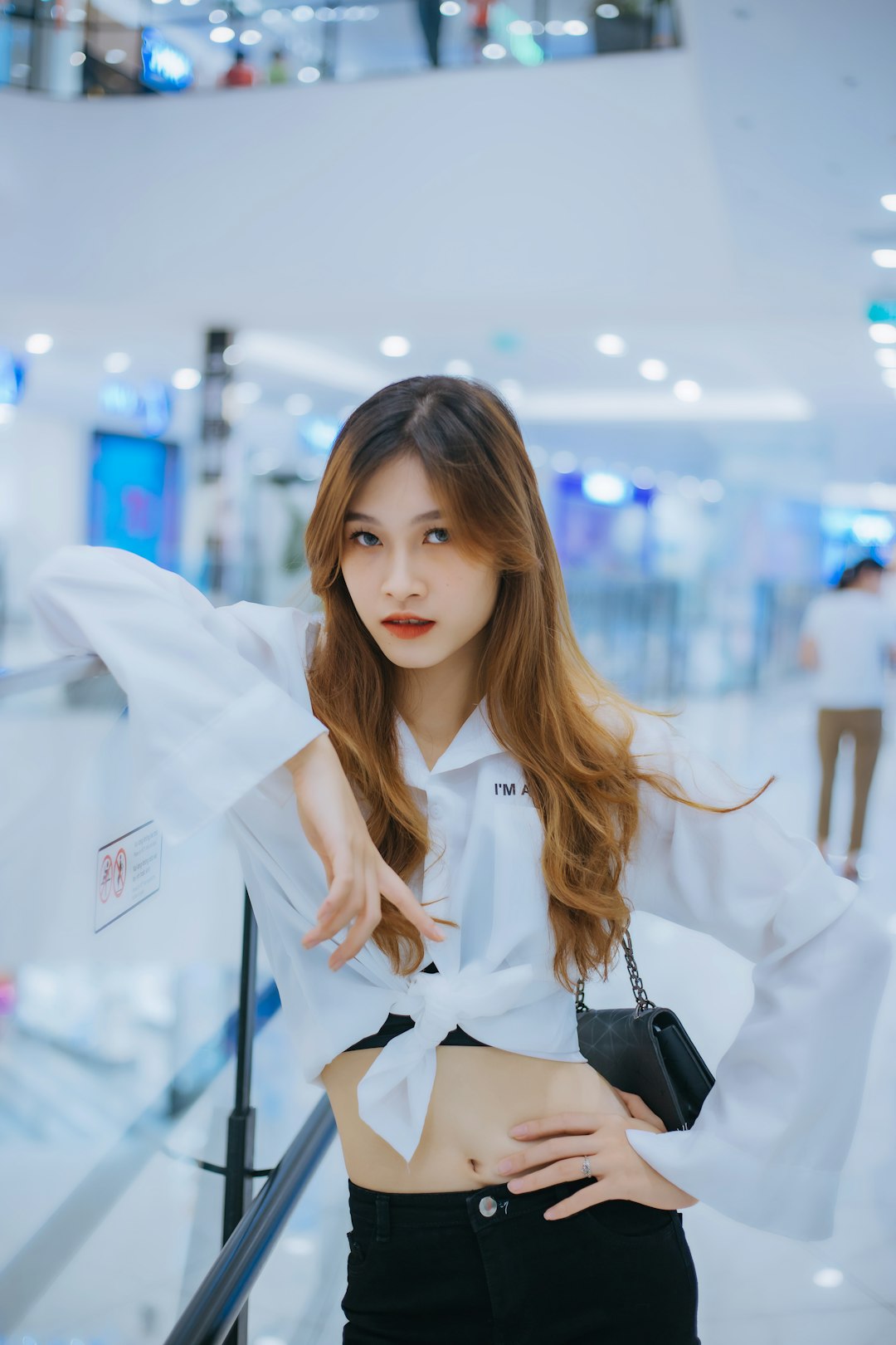 woman in white blazer holding black leather sling bag