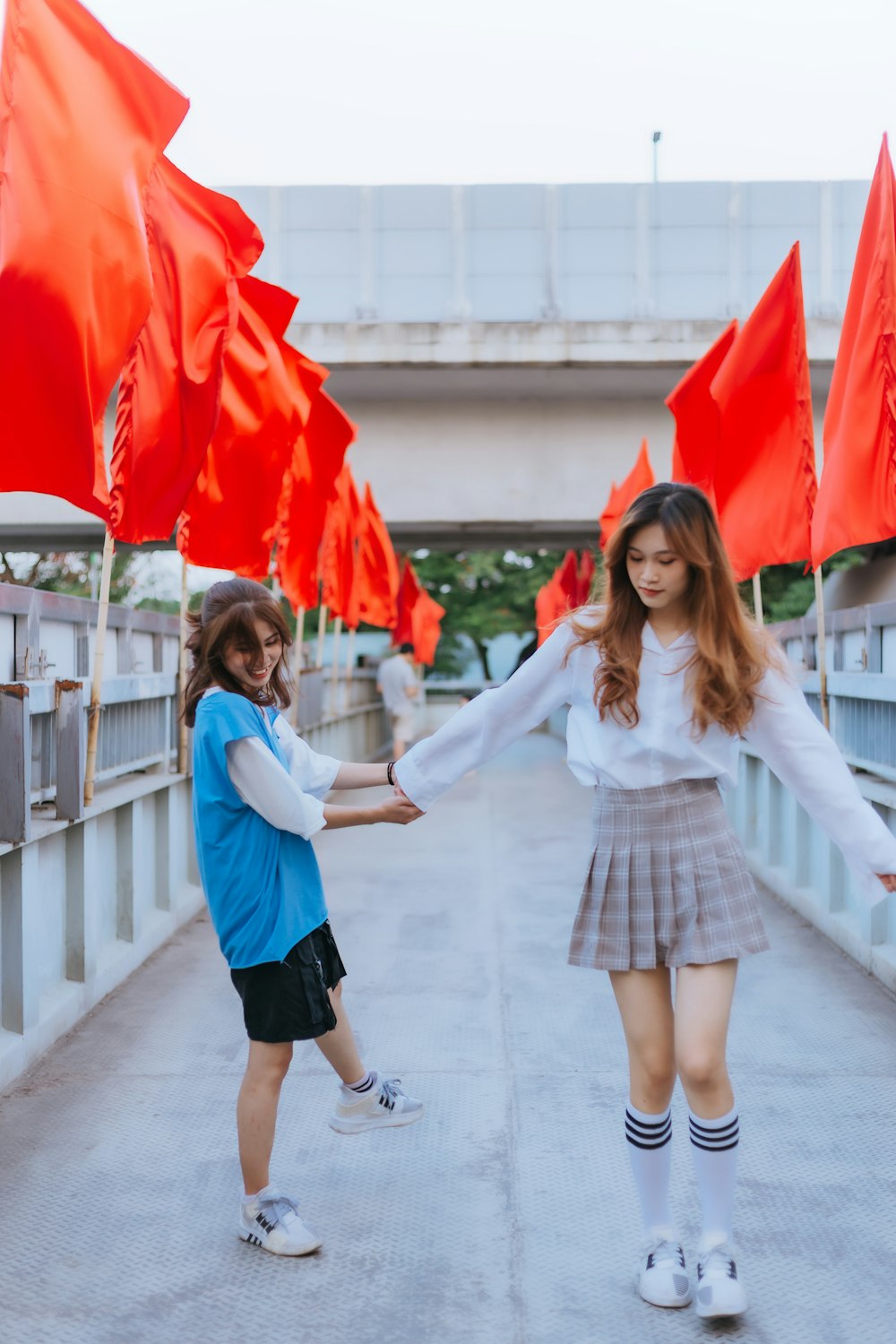 Femme en chemise blanche à manches longues et jupe bleue tenant un parapluie rouge